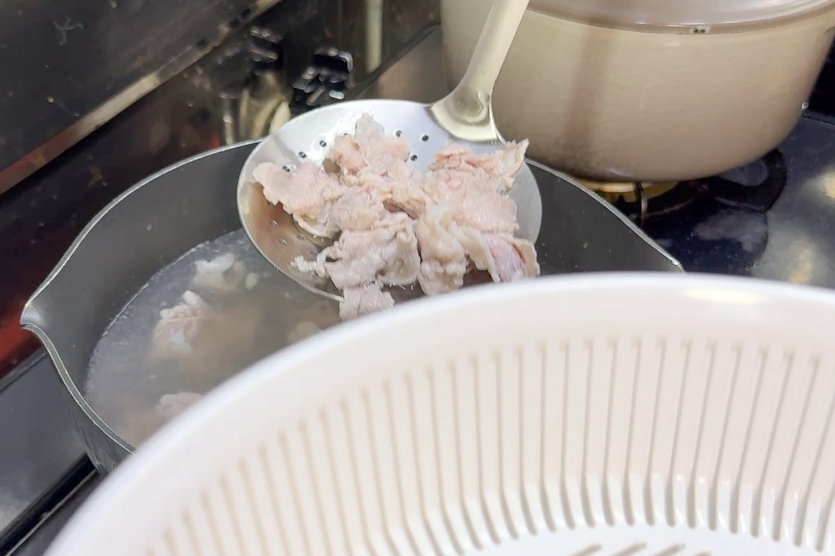 豚肉の湯通しして穴あきお玉で取り出す