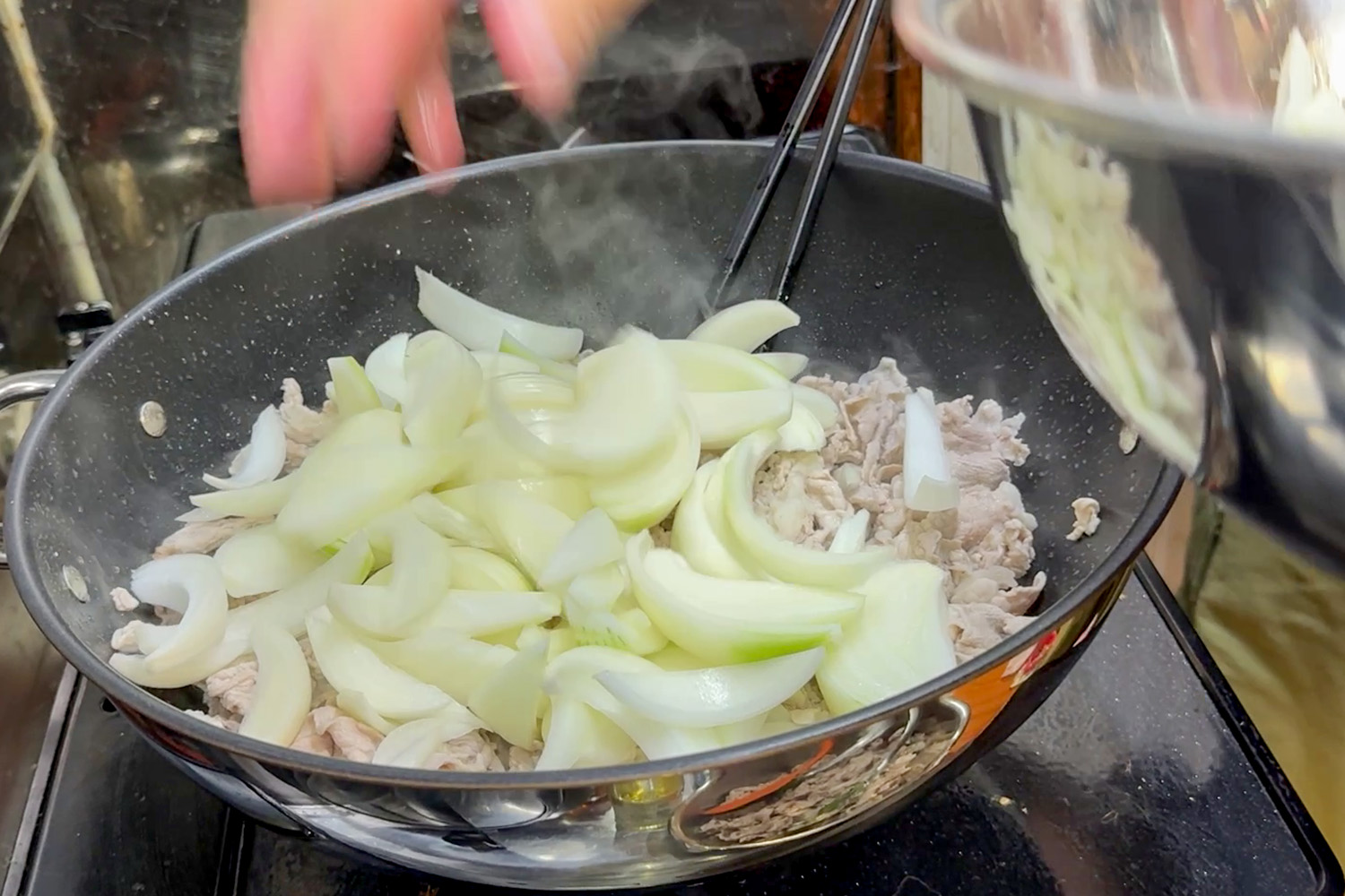 フライパンにくし切りの玉ねぎを入れる